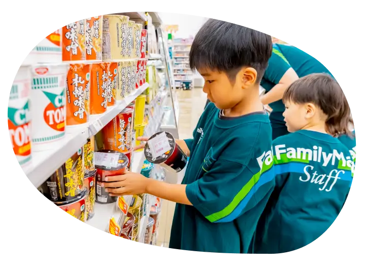 ファミリーマート店内。商品棚の商品を揃える男の子。