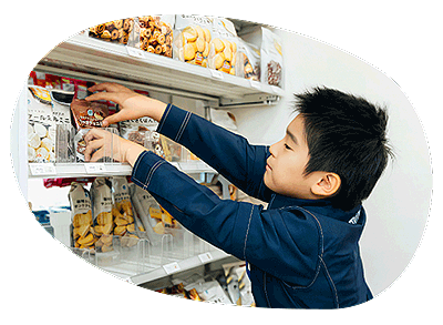 ファミリーマート店内。商品棚の商品を揃える男の子。