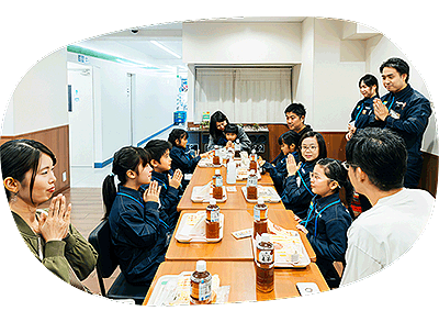 大きなテーブルを囲んで食事をする子どもたちと保護者。ファミリーマートスタッフも見守ります。