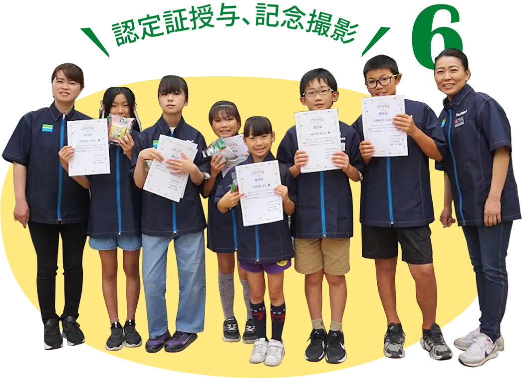 6. 認定証授与、記念撮影（写真：認定証を手に、 記念撮影をする こどもたちと店員