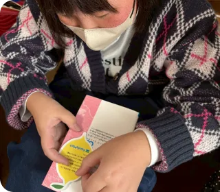 みんれもサンタ活動の様子：こどもがプレゼントにレモネードのステッカーを貼る様子
