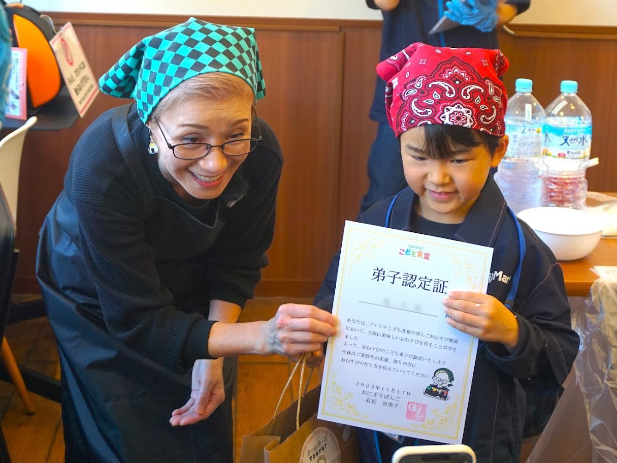 おにぎりぼんごの店主右近由美子氏から弟子認定書を受け取るこどもの様子