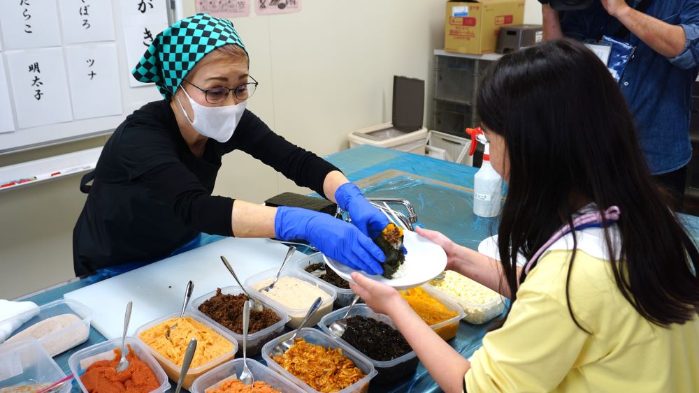 右近さんが握ったおむすびを参加者に渡している様子